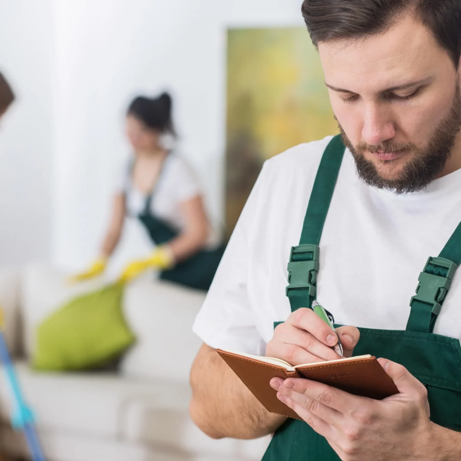 man-green-apron-writes-notebook-with-woman-background